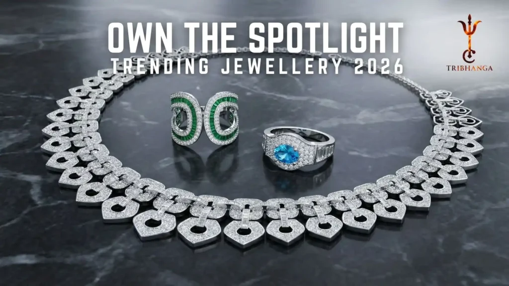 Diamond necklace and statement rings featuring emerald and blue gemstones on a dark marble background. Text reads: Own The Spotlight - Trending Jewellery 2026 by Tribhanga.